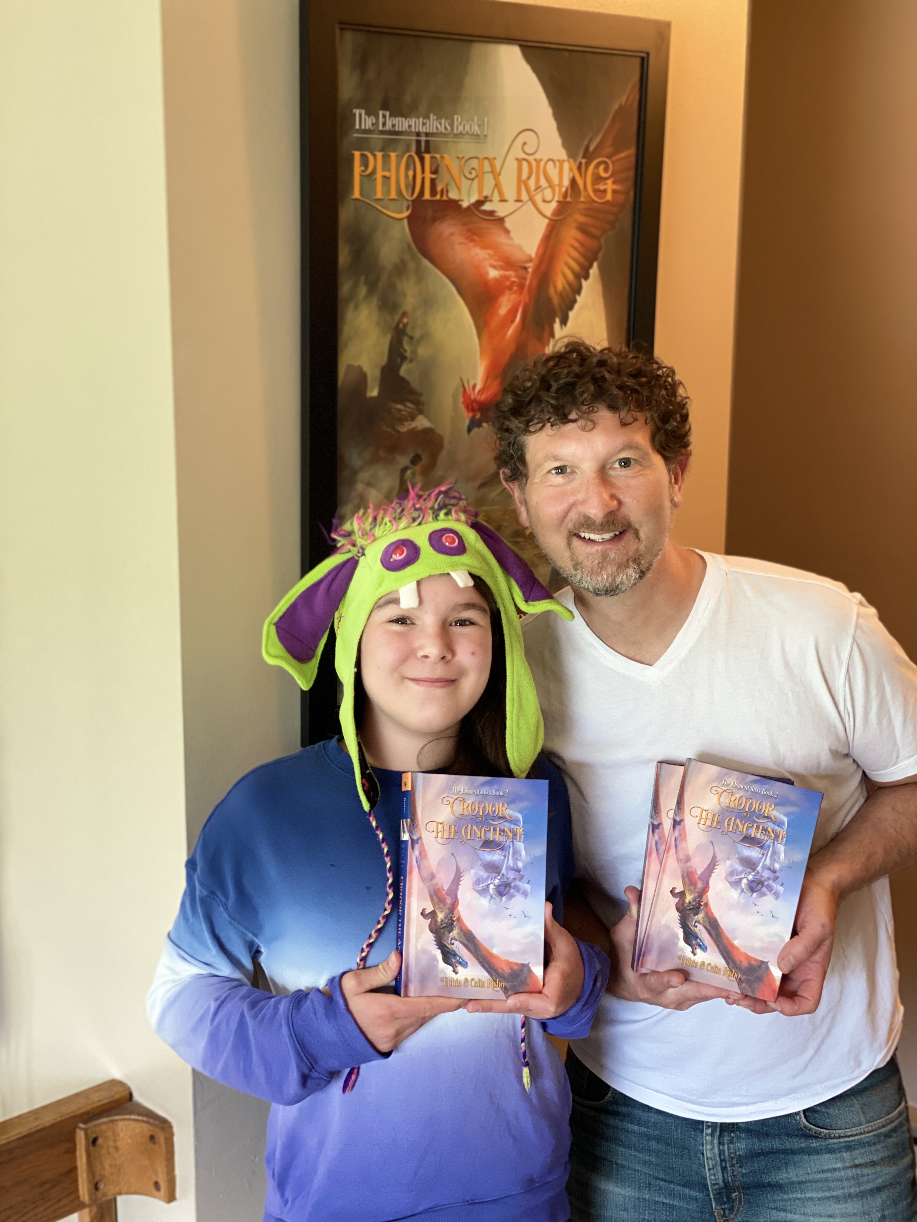 Ephie and Blue wearing a purple monster hat, holding copies of Crodor the Ancient