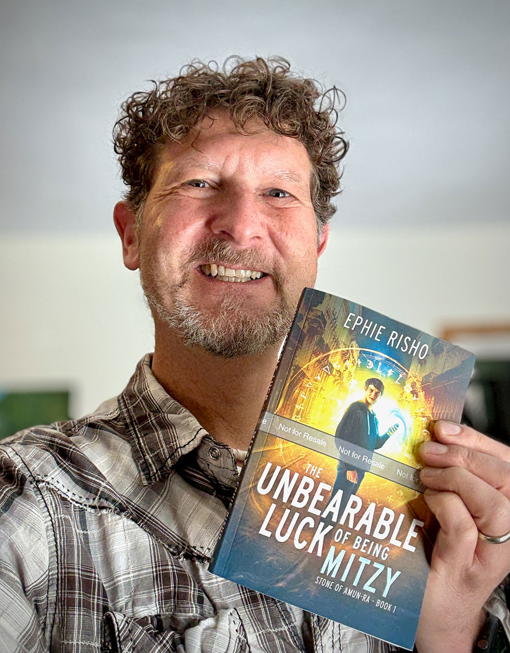 Ephie Risho with a copy of The Unbearable Luck of Being Mitzy, Book One of Stone of Amun-Ra