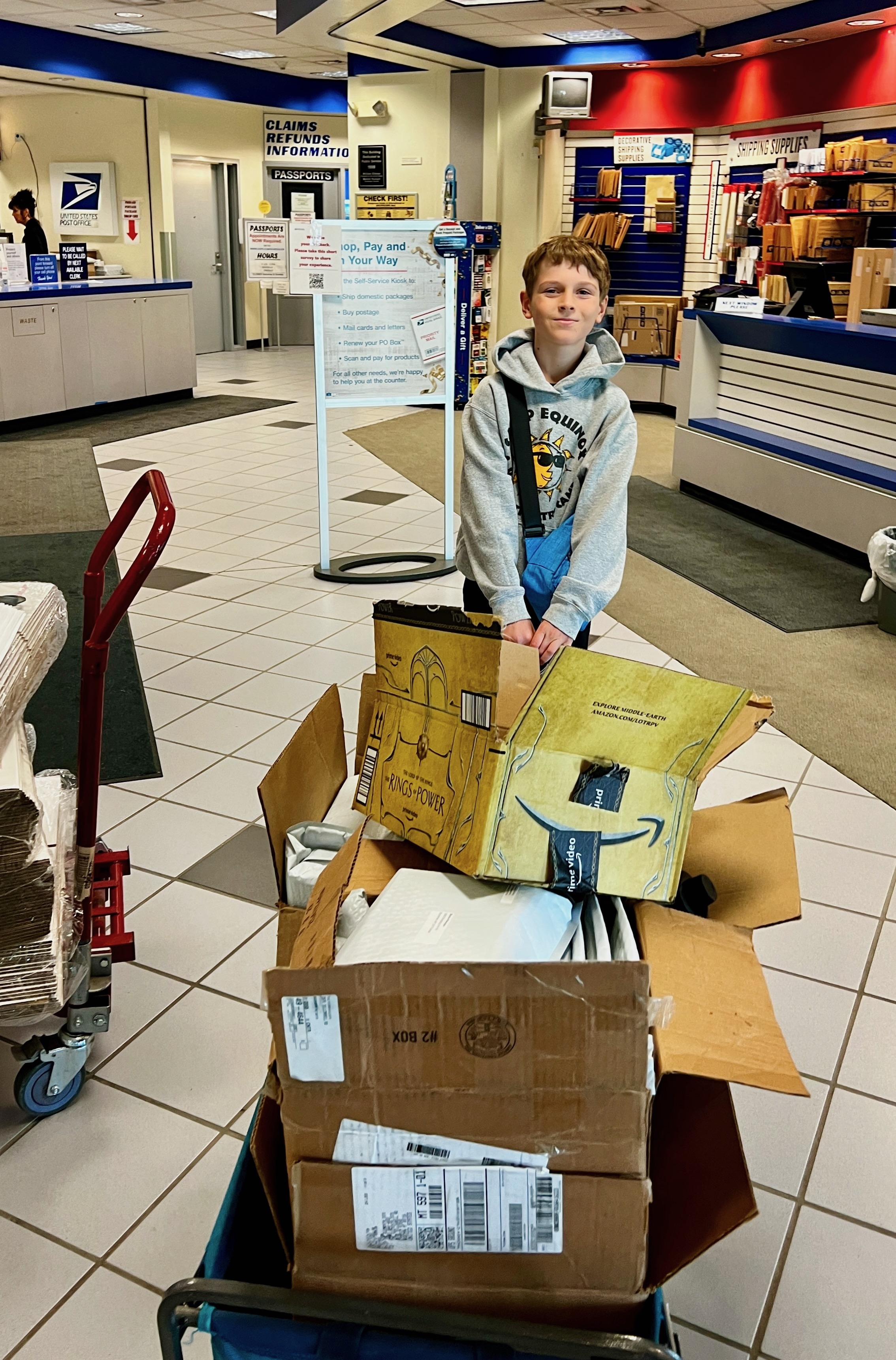 Joshua at the post office with a cart full of open Amazon boxes full of books ready to ship